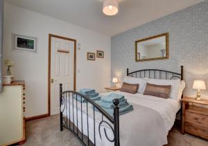 1 dormitorio con cama y espejo en la pared en Kingfisher Cottage, en East Down