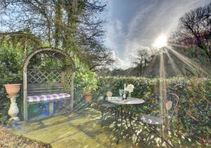 un dipinto di un giardino con panchina e tavolo di Kingfisher Cottage a East Down