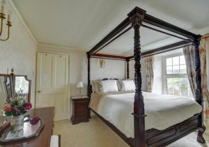 a bedroom with a canopy bed and a table at Laurel Cottage in Parracombe