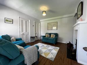 een woonkamer met 2 blauwe stoelen en een open haard bij The Cottage, Shalfleet House in Shalfleet