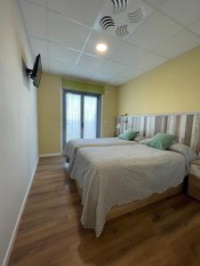 1 dormitorio con 2 camas y techo en Casa Costoya, en Arzúa