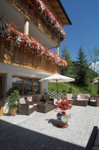 - une terrasse avec des chaises, un parasol et des fleurs dans l'établissement Pension Garden Hotel, à Colfosco