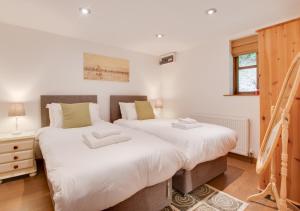 two beds in a bedroom with white walls and wooden floors at Devon Longstraw in Croyde