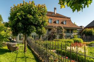 a fence in front of a house with a tree at Romantik Hotel Bären Dürrenroth in Dürrenroth