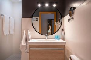 W łazience znajduje się umywalka i lustro. w obiekcie Hotel München City Center affiliated by Meliá w Monachium