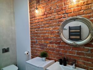 ein Badezimmer mit einer Backsteinwand und einem Spiegel in der Unterkunft Old Town WAWEL Premium Apartment - 60m2 in Krakau