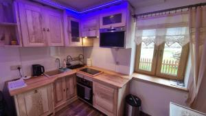 a kitchen with wooden cabinets and a sink and a window at Pokoje Pod Modrzewiami in Ciche