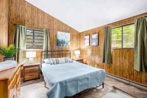 a bedroom with a bed and wooden walls at Modern w Fire Pit Deck, Grill & Hot Tub in Berkeley Springs