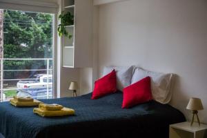 Un dormitorio con una cama con almohadas rojas y una ventana en Gente del Sur - Onas en Ushuaia