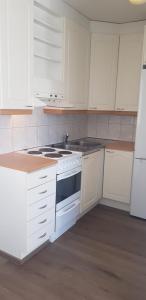 a kitchen with white cabinets and a stove top oven at Vuolteentie in Kauhajoki