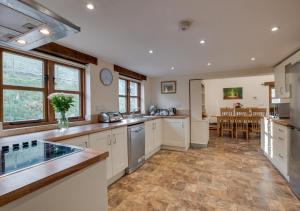 a large kitchen with white cabinets and a dining room at Mill Barn in Bishops Nympton