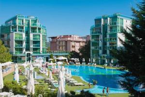 a swimming pool with white umbrellas and chairs and buildings at Двустаен апартамент в Приморско in Primorsko