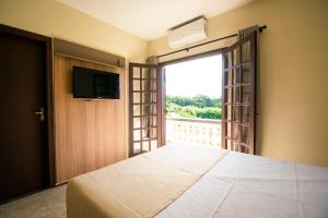 um quarto com uma cama e uma porta de vidro deslizante em Hotel Dona Paschoalina em Socorro