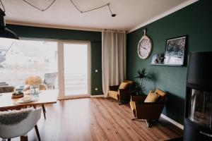 sala de estar con paredes verdes, mesa y sillas en SOONWALD Apartment mit Garten & Hot Tube, en Stromberg