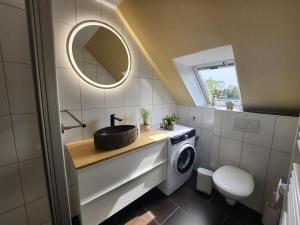 y baño con lavabo y lavadora. en Ferienwohnung Ammerland-Blüte, en Westerstede