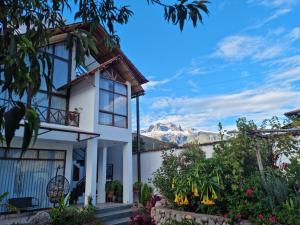 una casa blanca con montañas en el fondo en Flores de la Villa, en Huayoccari