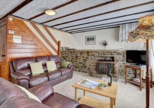 ein Wohnzimmer mit einem Ledersofa und einem Kamin in der Unterkunft Pusehill Cottage in Westward Ho