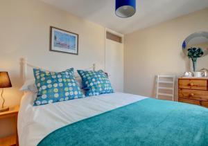 a bedroom with a bed with blue pillows and a dresser at Dune View Instow in Instow