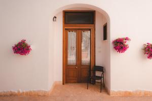 eine Holztür in einem weißen Gebäude mit Blumen in der Unterkunft Casina dei Preti in Conversano