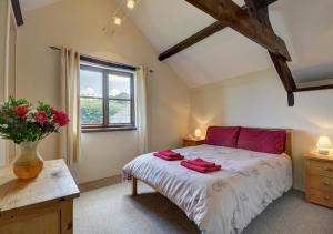 a bedroom with a bed with red pillows and a window at Button Stable in Bratton Fleming