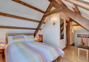 a bedroom with a large bed with wooden beams at Honeysuckle Cottage Welcombe in Welcombe