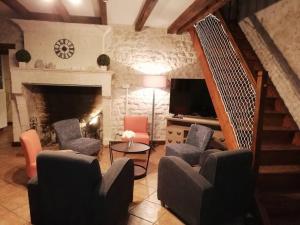 a living room with chairs and a tv and a fireplace at Maison charentaise à la campagne in Bécheresse
