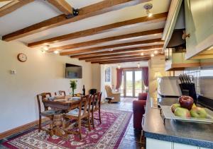 a kitchen and living room with a table and chairs at Honeysuckle Cottage Welcombe in Welcombe