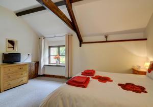 a bedroom with a large bed with red towels on it at Button Barn in Bratton Fleming