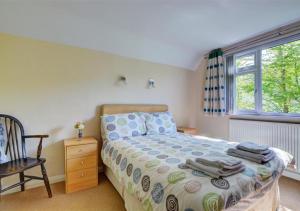 um quarto com uma cama, uma cadeira e uma janela em Cleeve em Barnstaple
