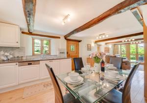 a kitchen and dining room with a glass table and chairs at Meadowside Barn in Meshaw