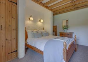 sypialnia z dużym białym łóżkiem i drewnianymi drzwiami w obiekcie Mole Cottage w mieście Parracombe