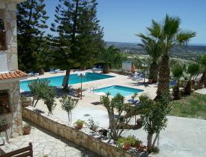 a swimming pool in a resort with palm trees at Rantzo Holiday Apartments in Pissouri