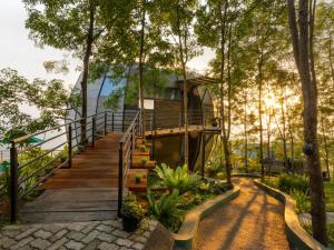a tree house in the forest with a wooden walkway at Green Acres Leisure Resort & Spa in Kandy