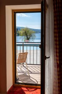 a chair on a balcony with a view of the water at Pension U Kostela in Frymburk