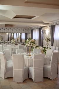 un salón de banquetes con mesas blancas, sillas y flores en Hotel IMPERYUM en Baia Mare