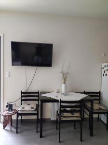 einen Esstisch mit 2 Stühlen und einen TV an der Wand in der Unterkunft Pegasus cosy house in Athen