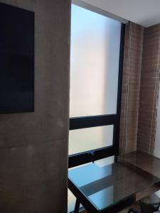 um quarto com uma mesa de vidro e uma janela em Aparta Suite - Centro Internacional - Mitika em Bogotá