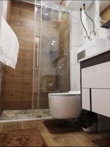 a bathroom with a shower with a toilet and a glass shower door at Стильная квартирка у моря in Batumi