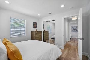 a white bedroom with a bed and a mirror at Casita Delray in Delray Beach