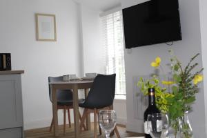 a dining room table with two chairs and a television on the wall at Kidsty Pike in Bowness-on-Windermere