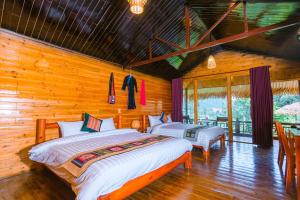 Duas camas num quarto com paredes de madeira em Bac Ha Lodge Retreat em Bắc Hà