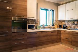 - une cuisine avec des placards en bois et un four micro-ondes dans l'établissement Penthouse with Stunning City Views, à Xewkija