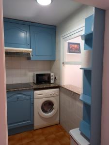 uma cozinha com armários azuis e uma máquina de lavar roupa em La Perla em Palamós