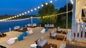 um deck com cadeiras, mesas e luzes na água em Lucas investment Q14-302 em Ştefăneştii de Jos