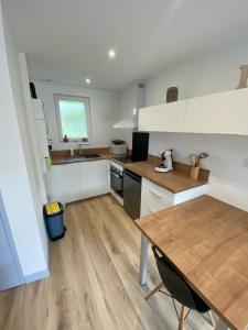 cocina con armarios blancos y mesa de madera en gîte avec chambre mezzanine pour 2 pers en Bréhal