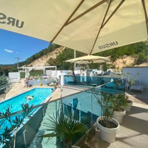 ein Pool mit Sonnenschirm und Pflanzen in einem Resort in der Unterkunft Riviera 990 - Resort & Restaurant in Eşelniţa