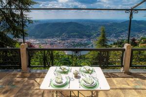 a table with plates and glasses on a balcony with a view at Villa I Tigli - by MyHomeInComo in Brunate