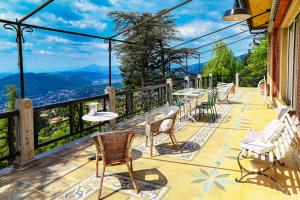 a balcony with chairs and tables and a view of mountains at Villa I Tigli - by MyHomeInComo in Brunate