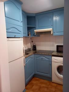 uma cozinha com armários azuis e um frigorífico branco em La Perla em Palamós