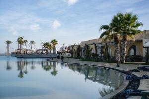 a pool of water with palm trees and buildings at Le Sidi - A TLT Signature Hotel in El Alamein